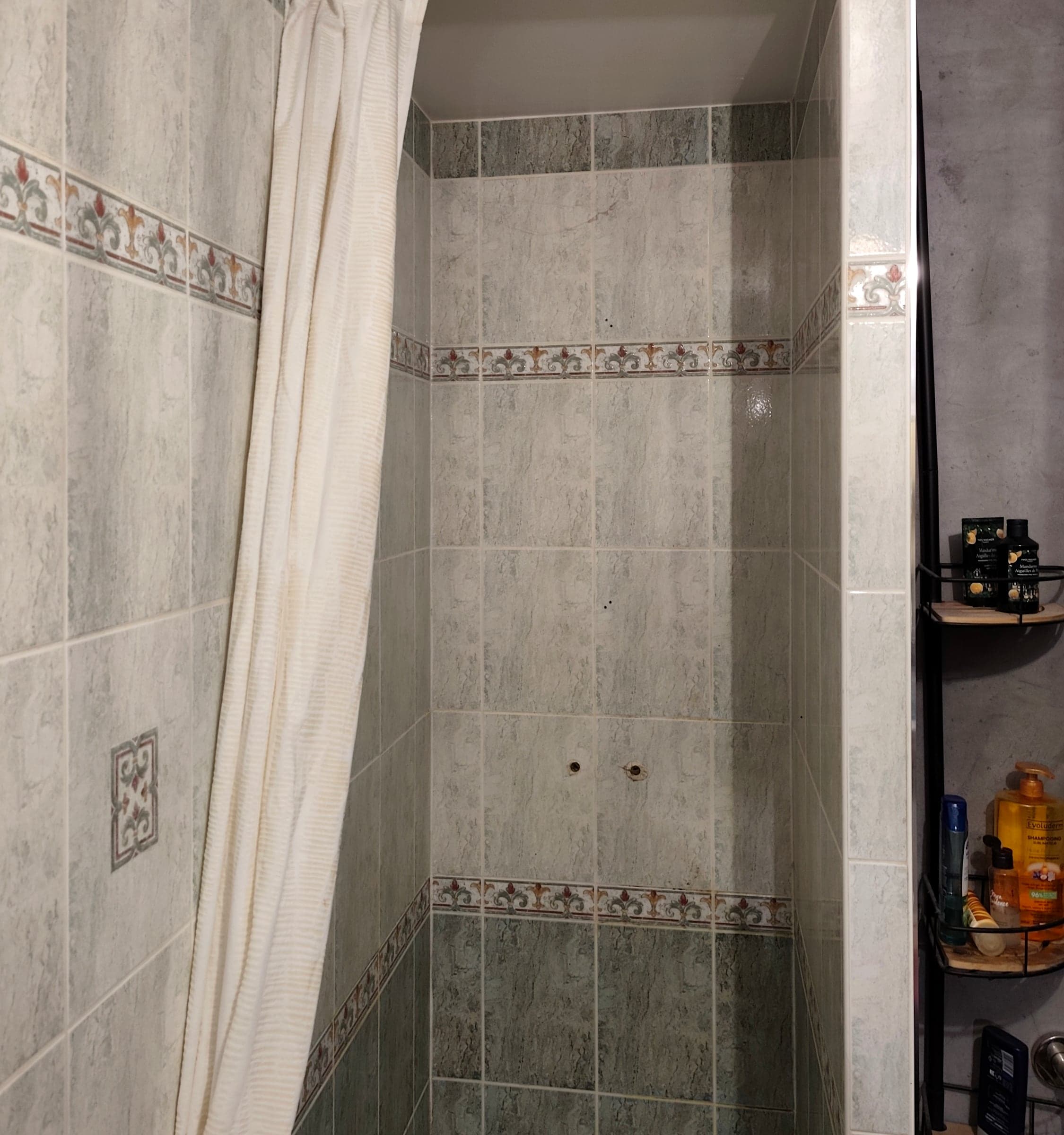 L’ancienne cabine de douche carrelée, avec son rideau et son receveur