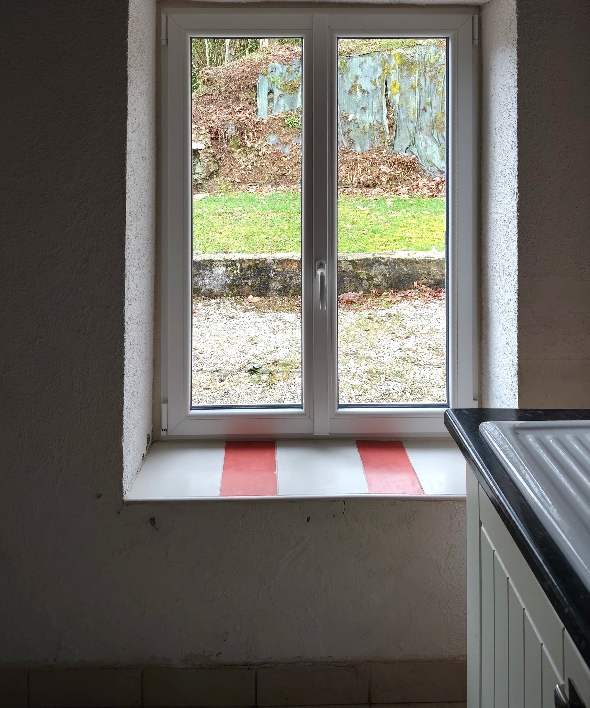 Fenêtre PVC blanche à deux vantaux vue de l’intérieur, dans une cuisine