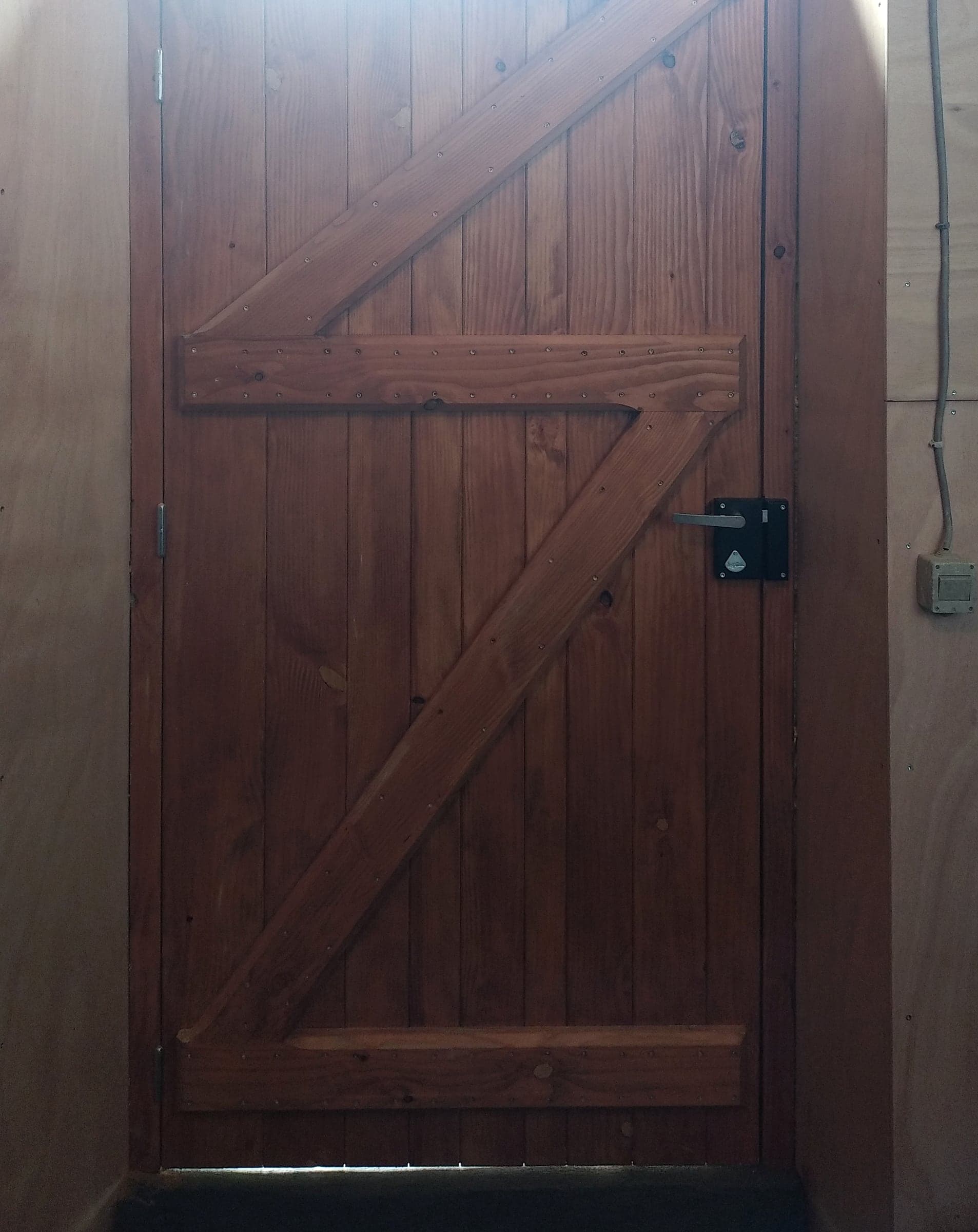 Face intérieure d’une porte en bois : traverses et écharpes en Z, serrure en applique