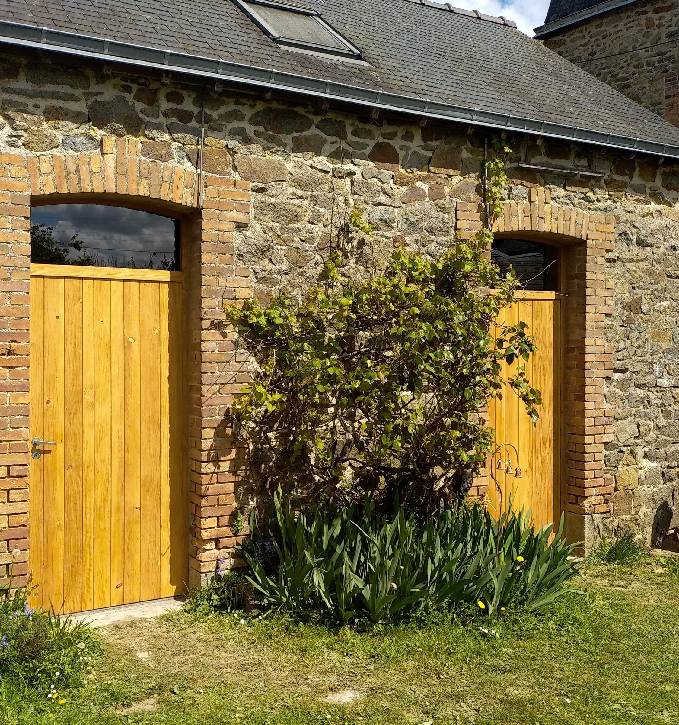 Dépendance en pierre et brique avec ses deux portes en bois neuves, vue du jardin