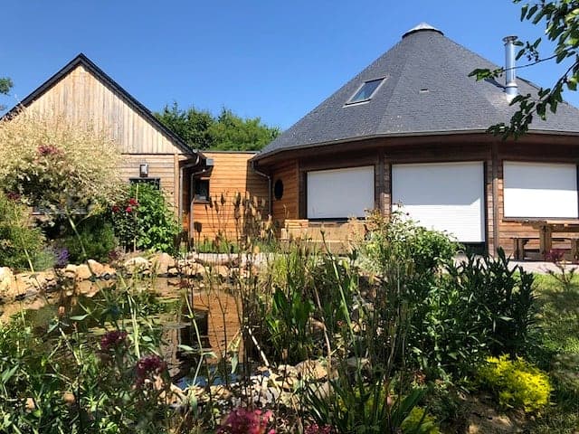 Maison en bois au toit octogonal, vue depuis le jardin et sa mare