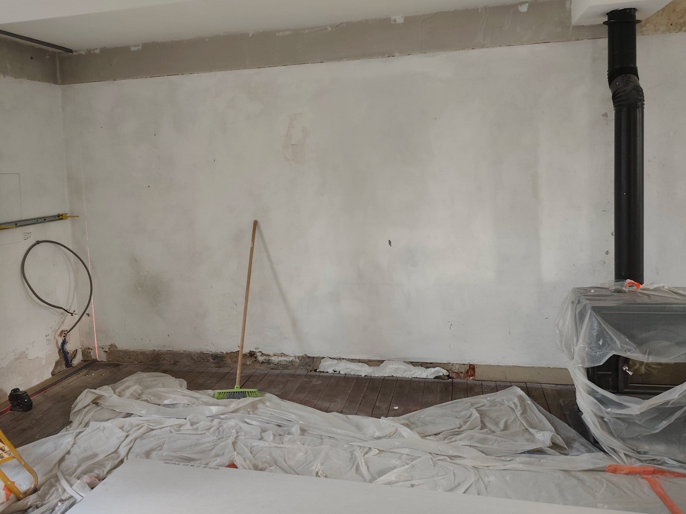 Mur enduit à nu avec le conduit d’un poêle, avant les travaux