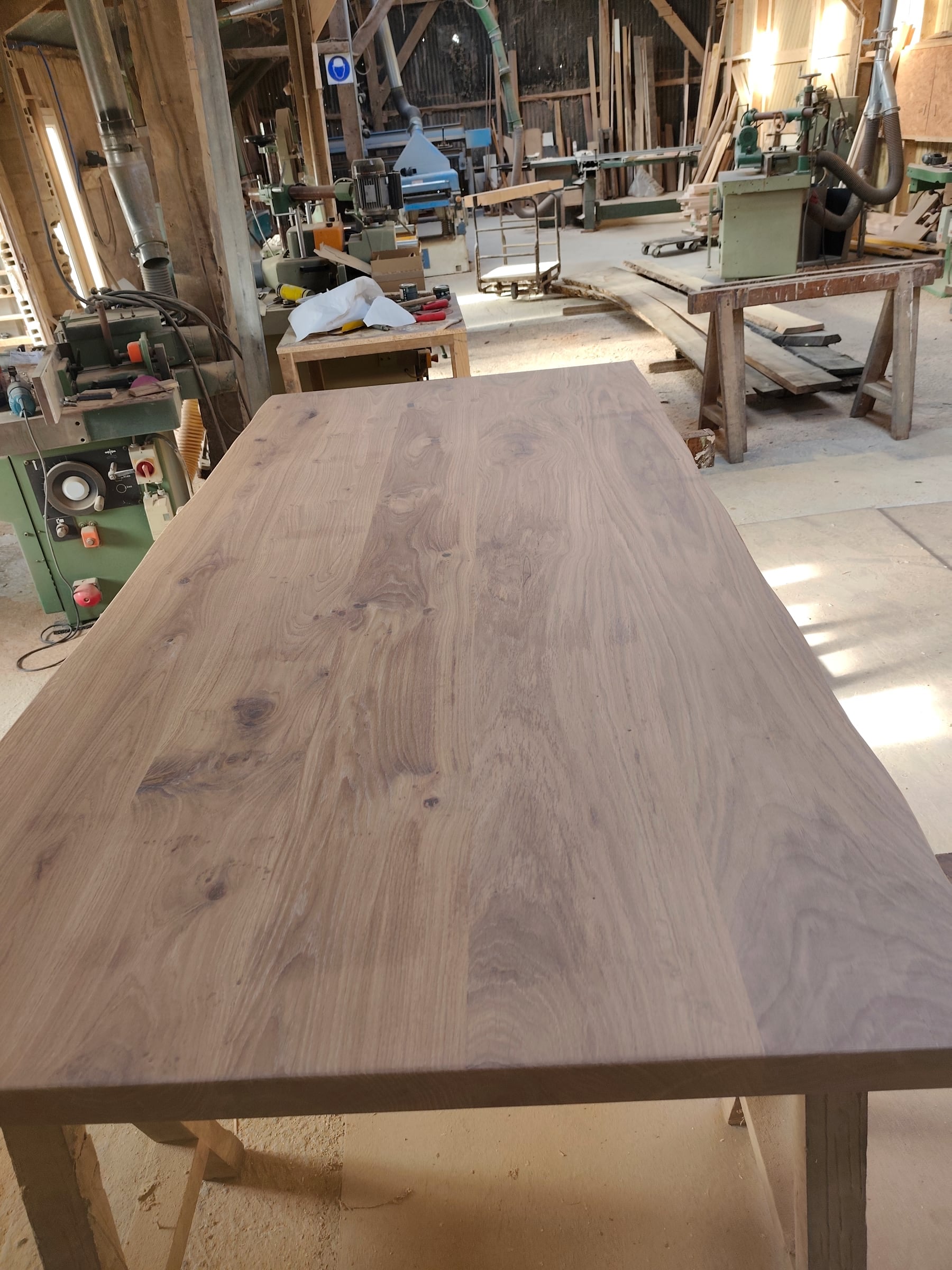 Plateau de table en chêne massif, poncé, posé sur des tréteaux dans l’atelier