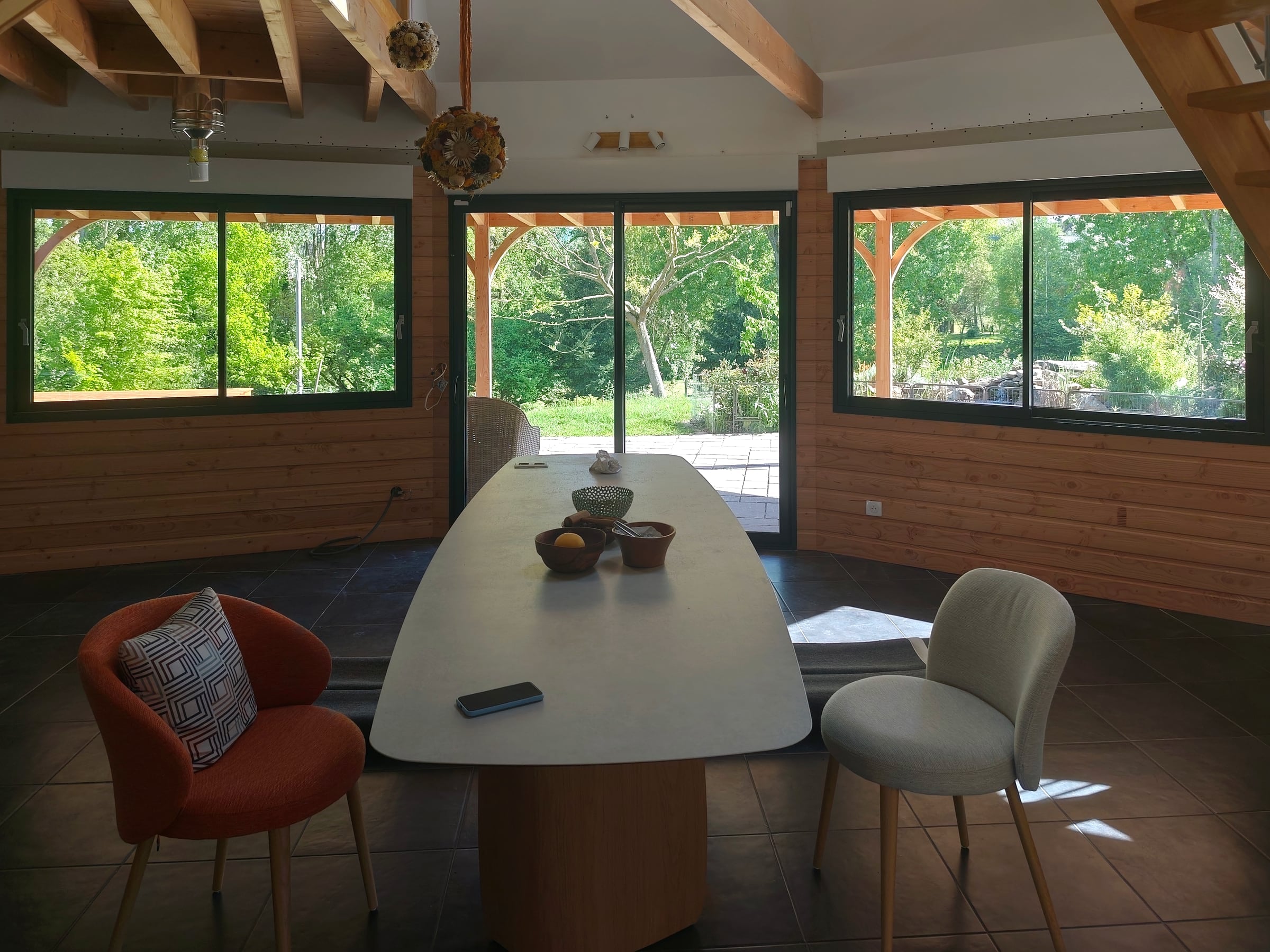 Pièce de vie octogonale en bois ouverte sur le jardin par trois baies coulissantes en aluminium