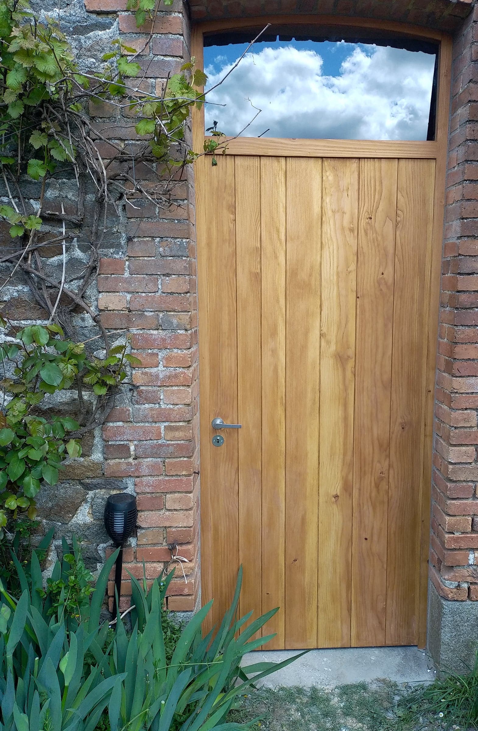 Seconde porte en bois massif dans son encadrement de brique, entourée de vigne